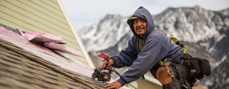 IWC roofer working on a roof with Utah mountains in the background
